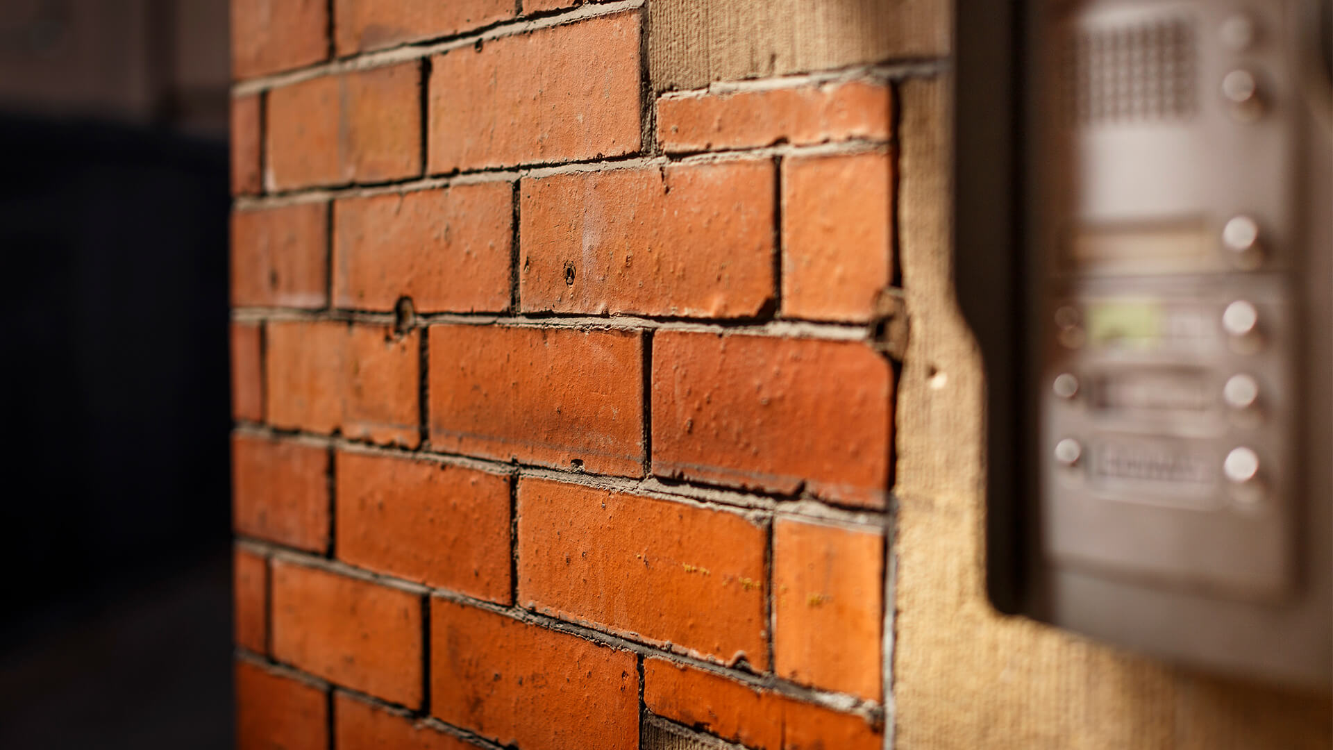 A close up of orange bricks and the intercom at 10-13 Thomas Street