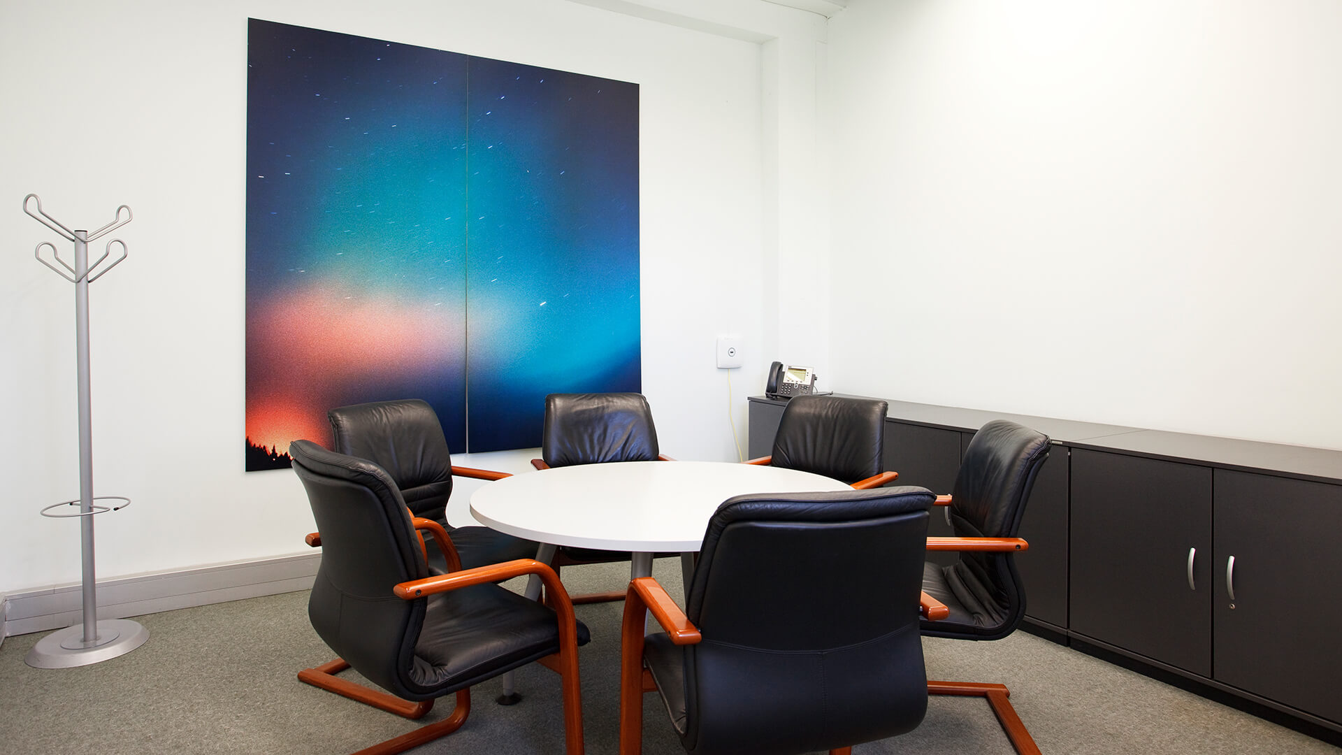 Black padded chairs surround a circular table in a Digital Depot meeting room