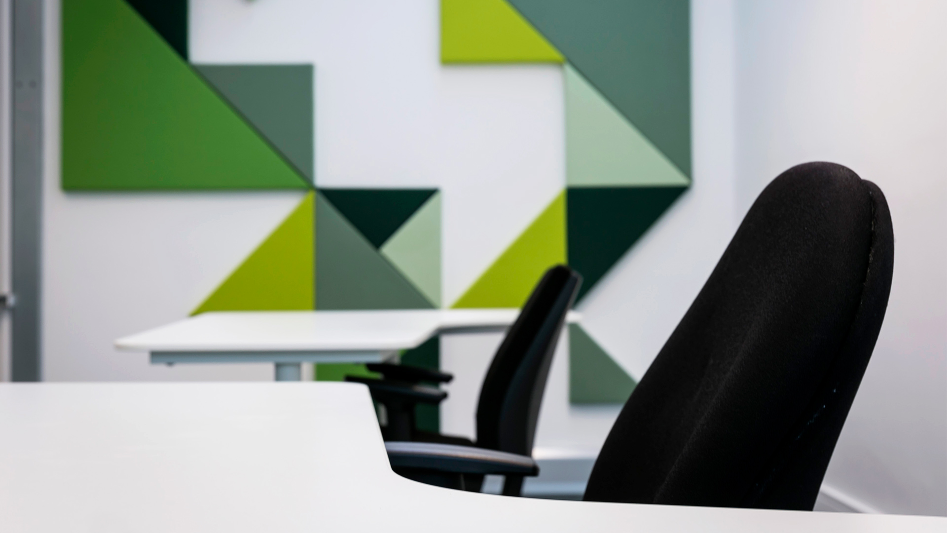 A close-up of office chairs with a modern, geometric mural on the far wall