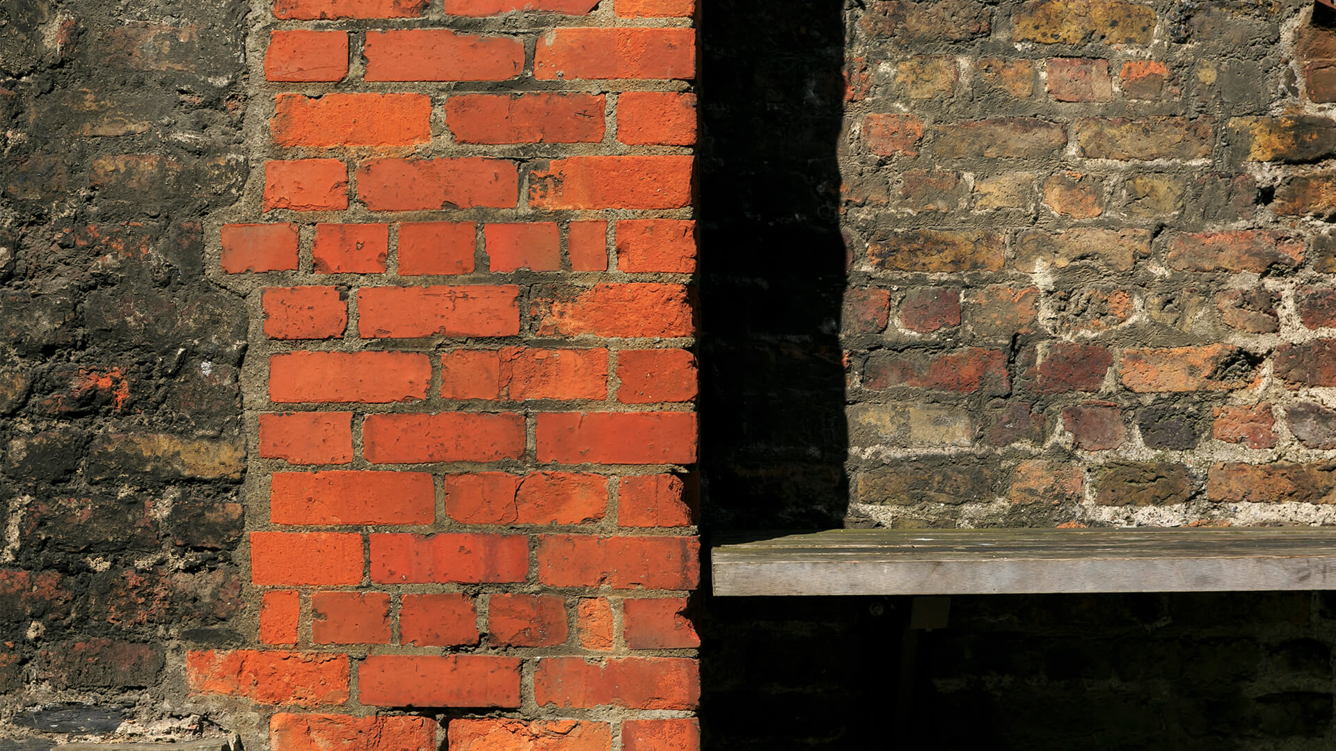 A close-up detail of a wall featuring bright orange bricks contrasting with older brown bricks