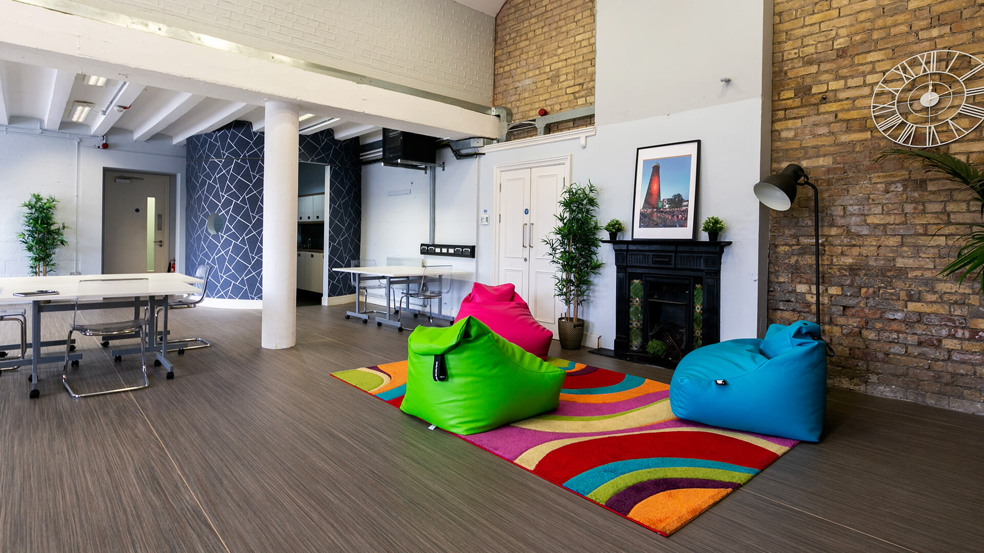 Brightly coloured beanbags sit on a rug in an open-plan office space