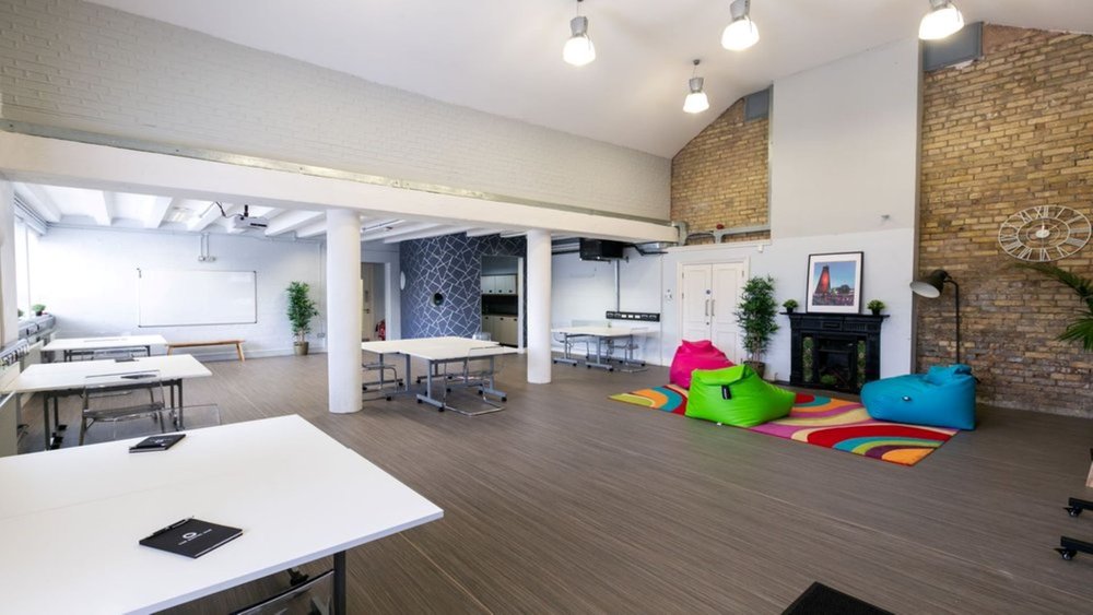 A workspace at The Digital Hub called iD8 Studio. The room is set up like a classroom with tables and chairs and brightly coloured bean bags in the corner.