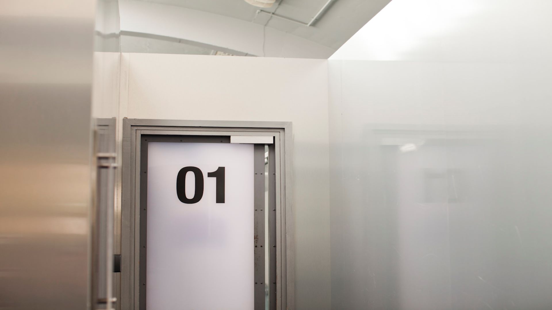 Picture of the external door of Bay 1 at The Digital Hub. The door has the number 1 on it and the walls left and right are grey.